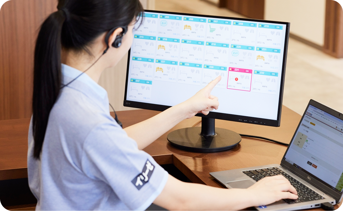 見守りシステムの画面で入居者様の状況を確認するスタッフ