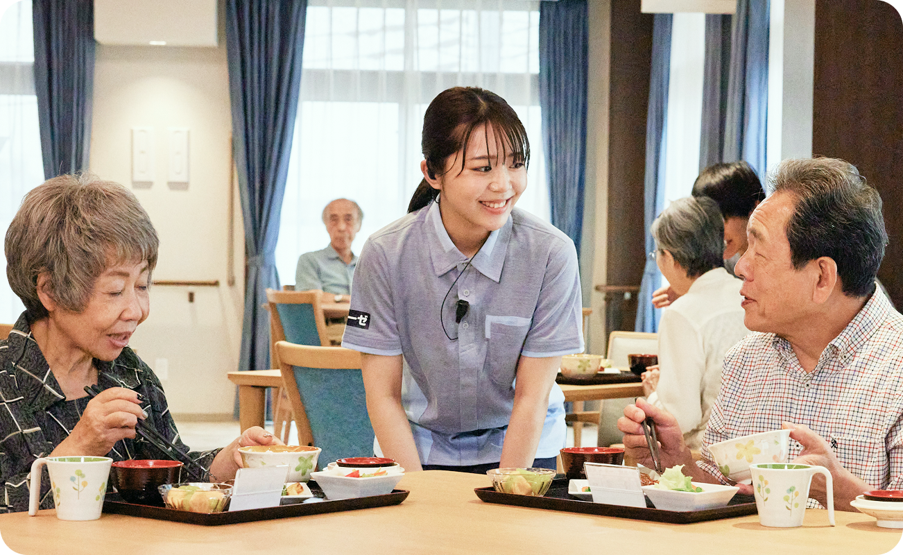 食事の配膳をしながら入居者様と談笑するスタッフ